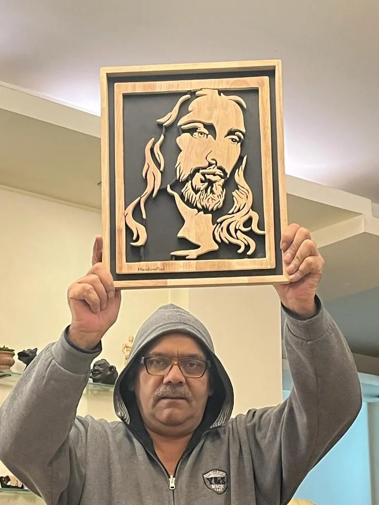 Subodh Kumar holding a finished scroll saw panel above his head
