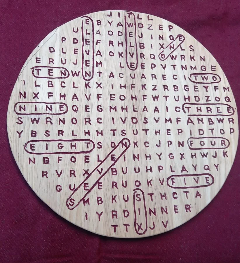 Wall clock with the hours hidden in a cut letter grid