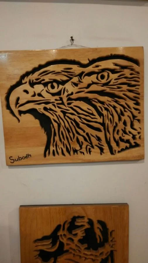 Eagle head cut on a wood panel and signed Subodh
