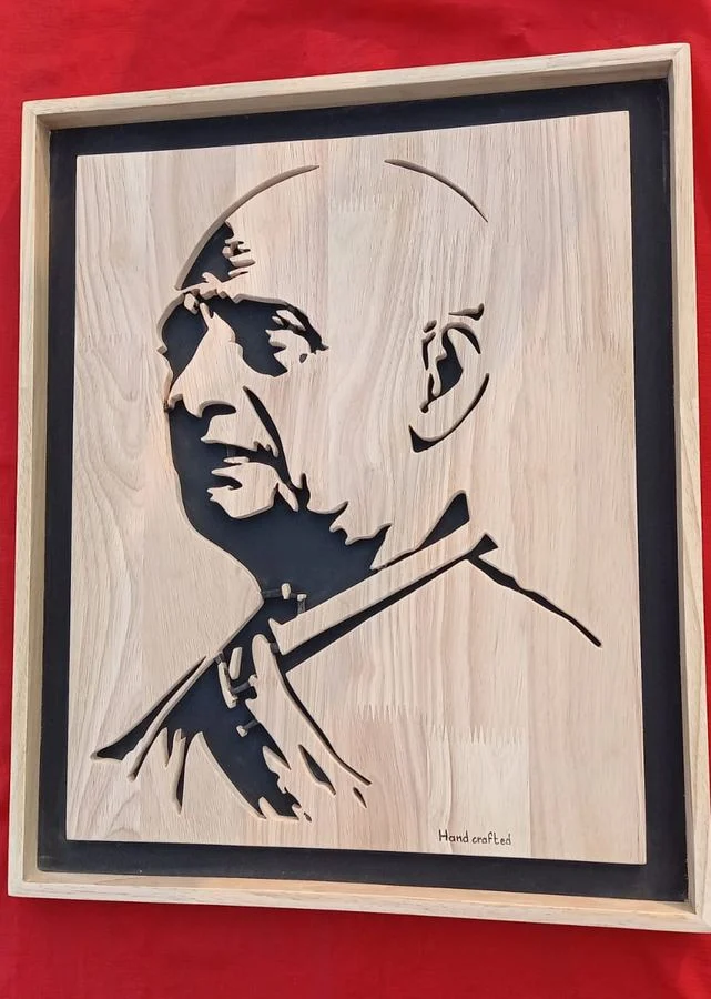 Profile portrait cut in wood, mounted on a black backing board